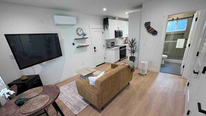 A modern living room with a sofa, TV, and dining area.