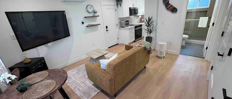 Una sala moderna con sofá, televisión y comedor.