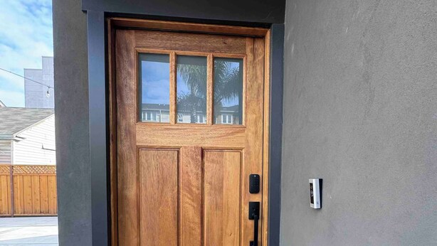 A wooden front door with a glass panel and a black handle.