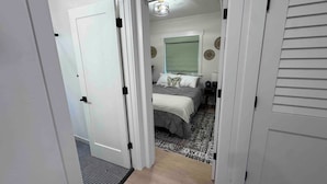 A bedroom with a bed, a nightstand, a lamp, and a window with blinds.