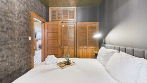A bedroom with a bed, wooden wardrobe, and a nightstand with a lamp.