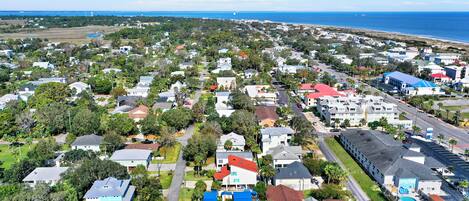 An aerial view of a residential area with houses, roads, and a beach in the background.