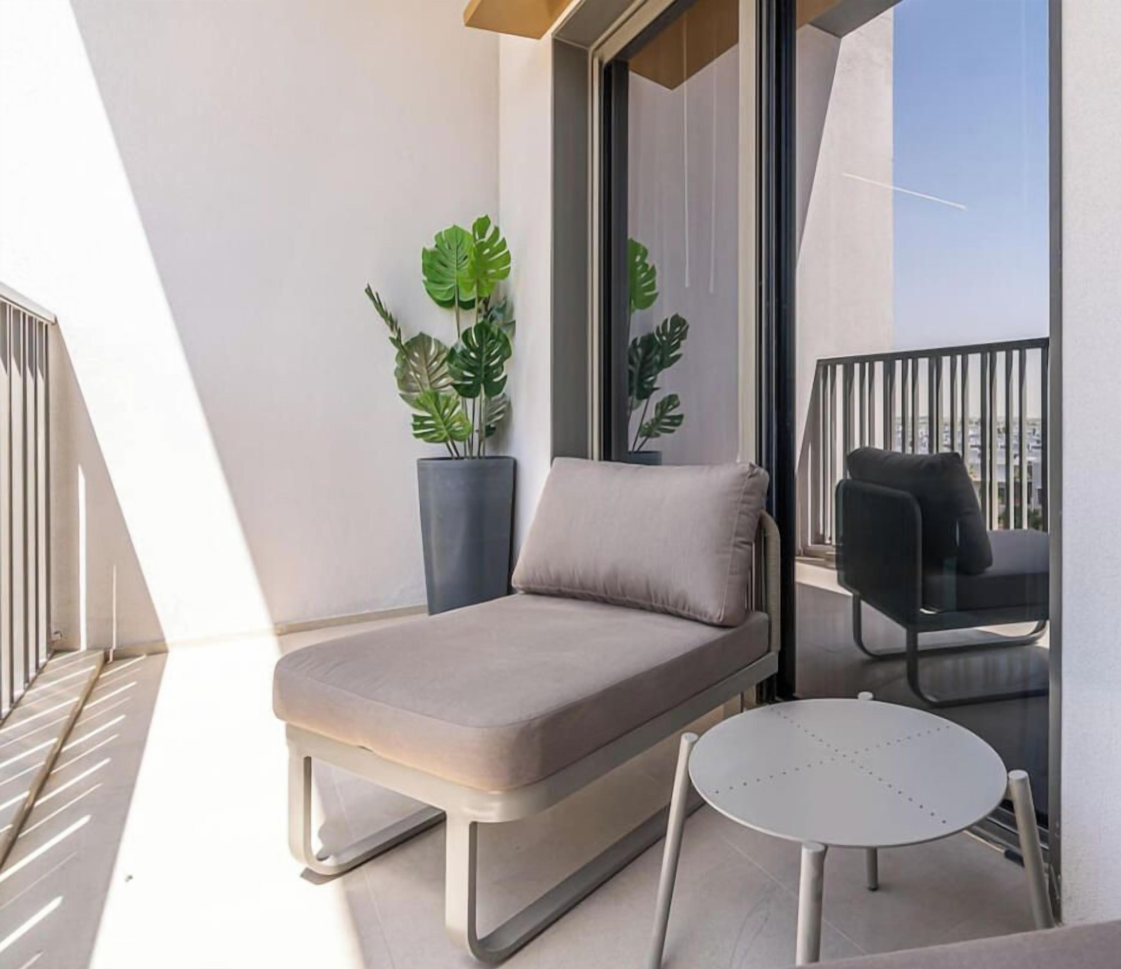 Een balkon met een bank, een tafeltje en twee stoelen. Er staan potplanten en er is uitzicht over de stad.