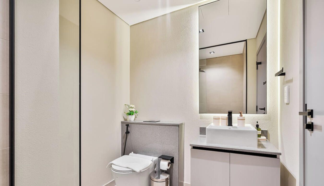 Een moderne badkamer met toilet, wastafel en spiegel.