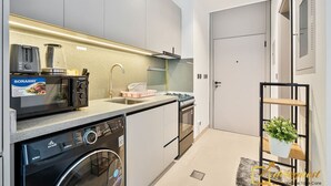 A compact kitchen with a dishwasher, microwave, toaster, and sink. - Posh Studio in MBR by Deleguest (Dubai)