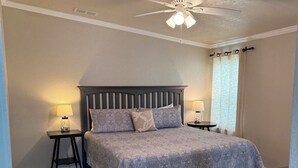 Una camera da letto con un letto, due comodini, una ventola a soffitto e una finestra con tende.