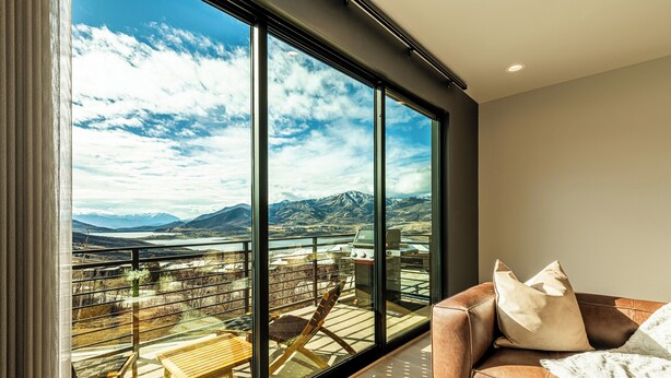 Una habitación moderna con ventanas amplias, un sofá de cuero y una mesa de madera.