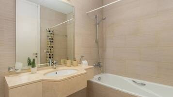 Een badkamer met twee wastafels, een bad, een douche en een grote spiegel.