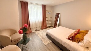 Una camera d'albergo moderna con un letto, una sedia, un piccolo tavolino con un vaso di fiori e un armadio.