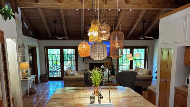 A spacious kitchen with a large island, wooden cabinets, and hanging pendant lights.
