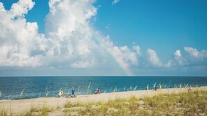 A beach with people, grass, and a clear sky.