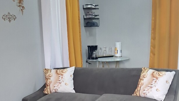 A grey sofa with floral cushions, a white air conditioner, and yellow curtains. - Enchanting private apartment with AC in lively Higuey (Higuey)