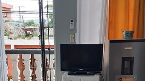 A living room with a flat-screen TV, a white cabinet, and a refrigerator. - Enchanting private apartment with AC in lively Higuey (Higuey)