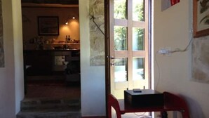 Um quarto com área de refeições, incluindo uma mesa e cadeiras, janela com vista e cozinha ao fundo.