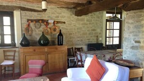 Um quarto rústico com parede de pedra, móveis de madeira, uma mesa de jantar e um sofá com almofada.