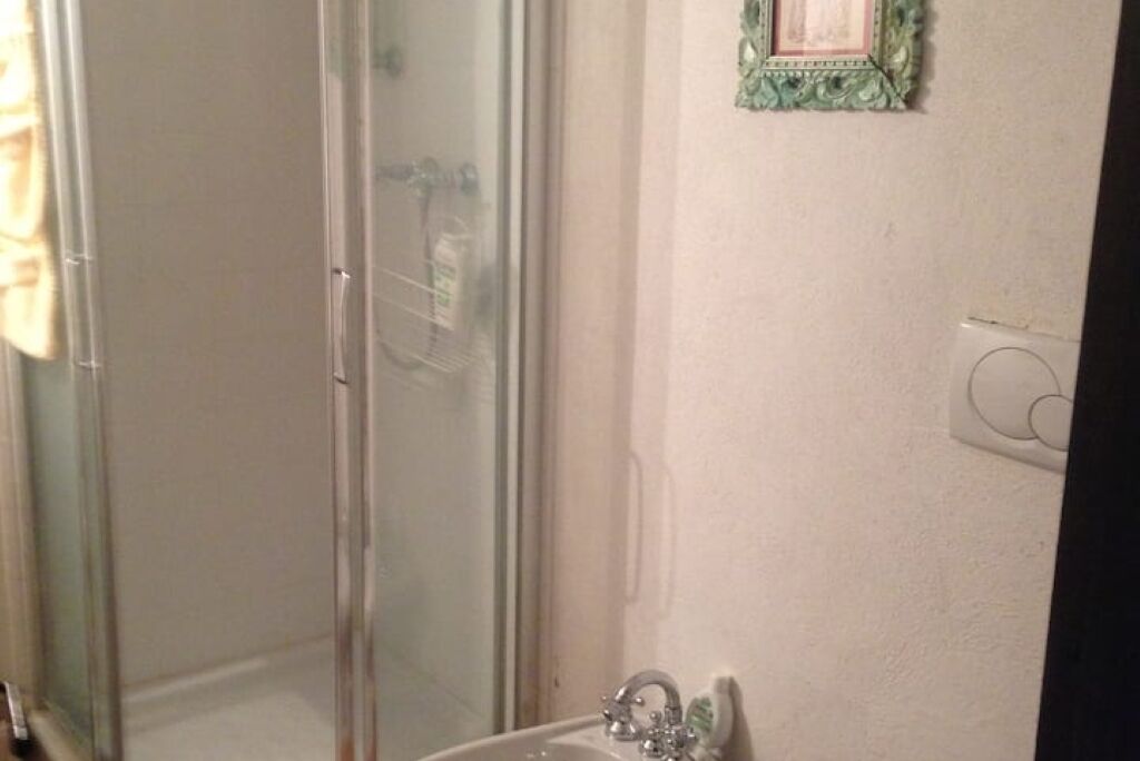 Un baño con cabina de ducha de vidrio, un lavabo con espejo y un cuadro en la pared.