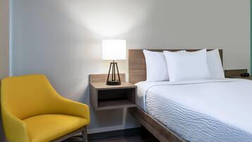 Une chambre d’hôtel avec un lit, une table de chevet avec une lampe et une chaise jaune.