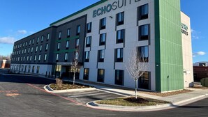 Een modern hotelgebouw met de naam 'Echosuites' op de gevel. Het heeft een raster van ramen en een groene accentmuur.