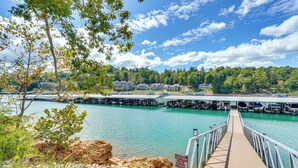 A pier leading to a dock with a caution sign, a calm lake, and a forested hillside in the background. - Private Boat Slip, Scenic Views: Norris Lake Condo (Morley)