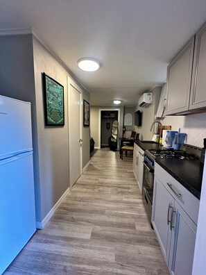 A kitchen with a refrigerator, stove, and cabinets.