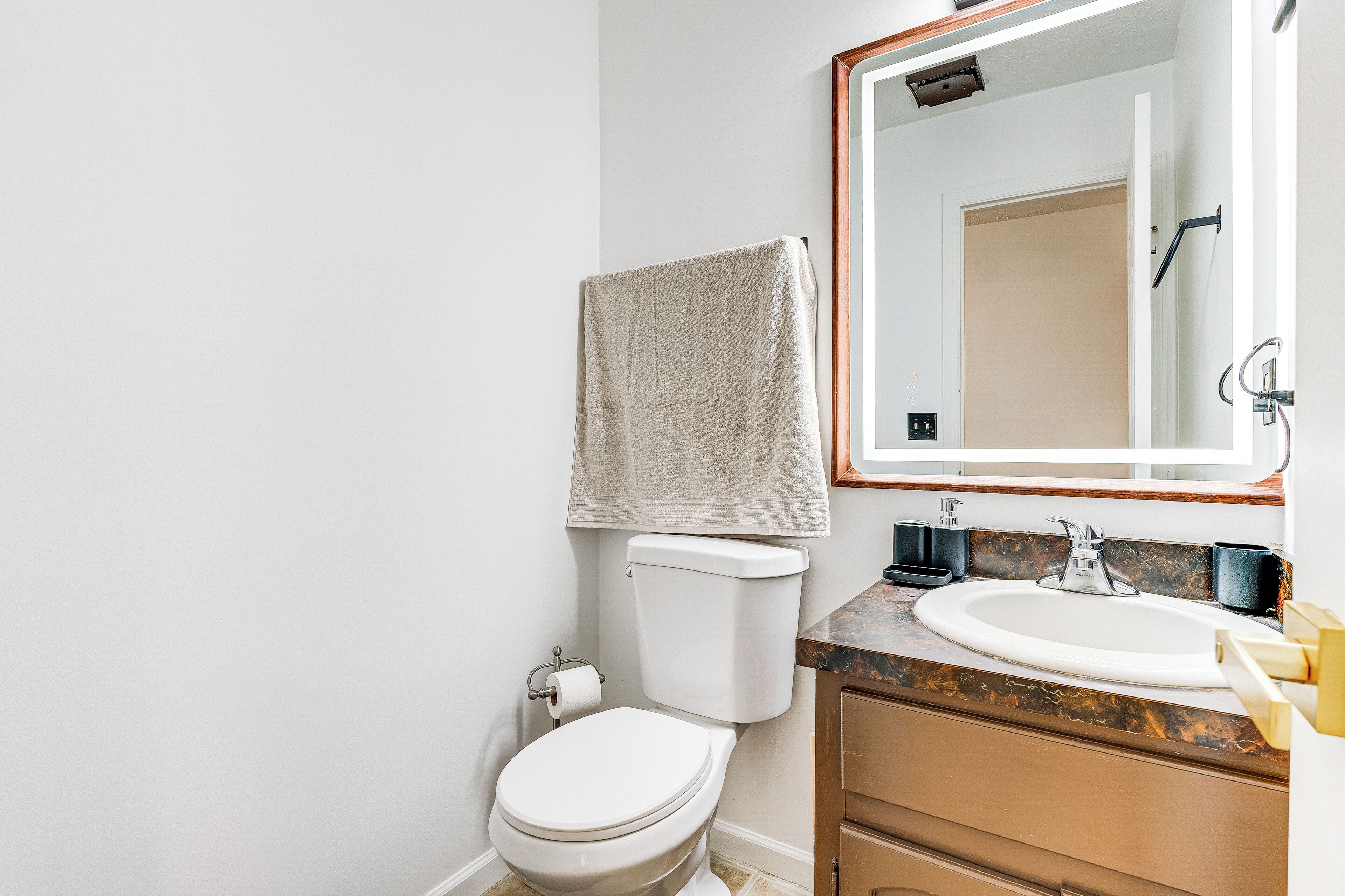 Een badkamer met toilet, wastafel en spiegel.