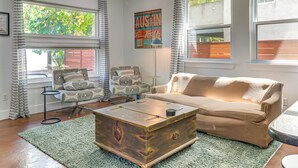 A living room with a wooden coffee table, a beige sofa, patterned armchairs, and a green rug. - Cowboy Pool & Balcony: Home 1 Mi to Dtwn Austin! (Austin)