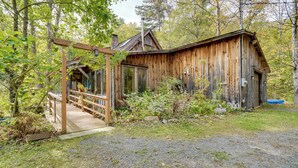 Une cabane rustique en bois, dotée d’une terrasse en bois et d’un porche abrité.