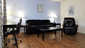 A living room with a black leather sofa, a black leather chair, a wooden coffee table, and two lamps on either side of the sofa. - Pleasant corporate apartment with AC in Donna (Donna)