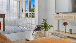Un salon moderne comprenant un téléviseur, un canapé, une table basse et un coin repas avec des chaises.