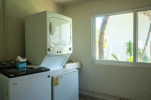 A laundry room with a washing machine, a dryer, and a window with a view of trees.