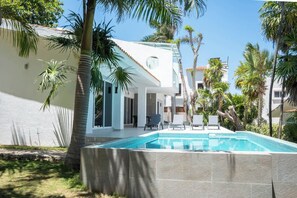Ein modernes Gebäude mit Swimmingpool, Palmen und blauem Himmel.