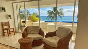 Ein Zimmer mit Korbmöbeln, Meerblick und Fliesenboden.