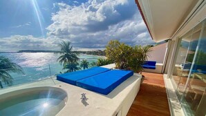 Ein Balkon mit Whirlpool, blauen Kissen und Meerblick.