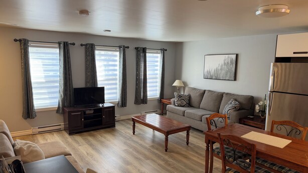 A living room with a TV, sofa, dining table, chairs, and a refrigerator. - 3 Bed 2.5 bath on Queen pet friendly (St. John's)