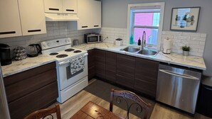 A modern kitchen with white cabinets, a stainless steel refrigerator, a microwave, and a stove. - 3 Bed 2.5 bath on Queen pet friendly (St. John's)