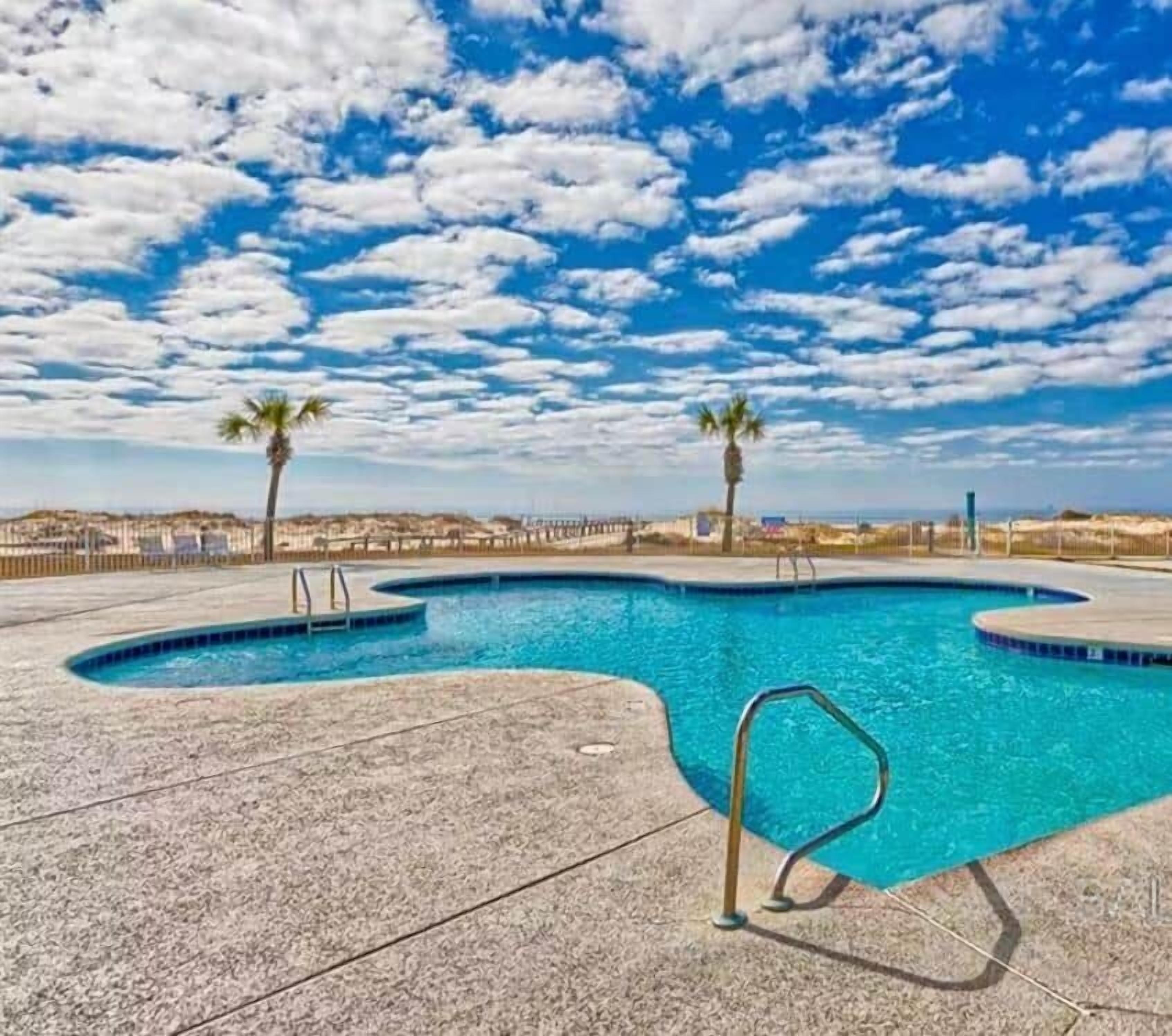 A swimming pool with a curved design, surrounded by a concrete deck.
