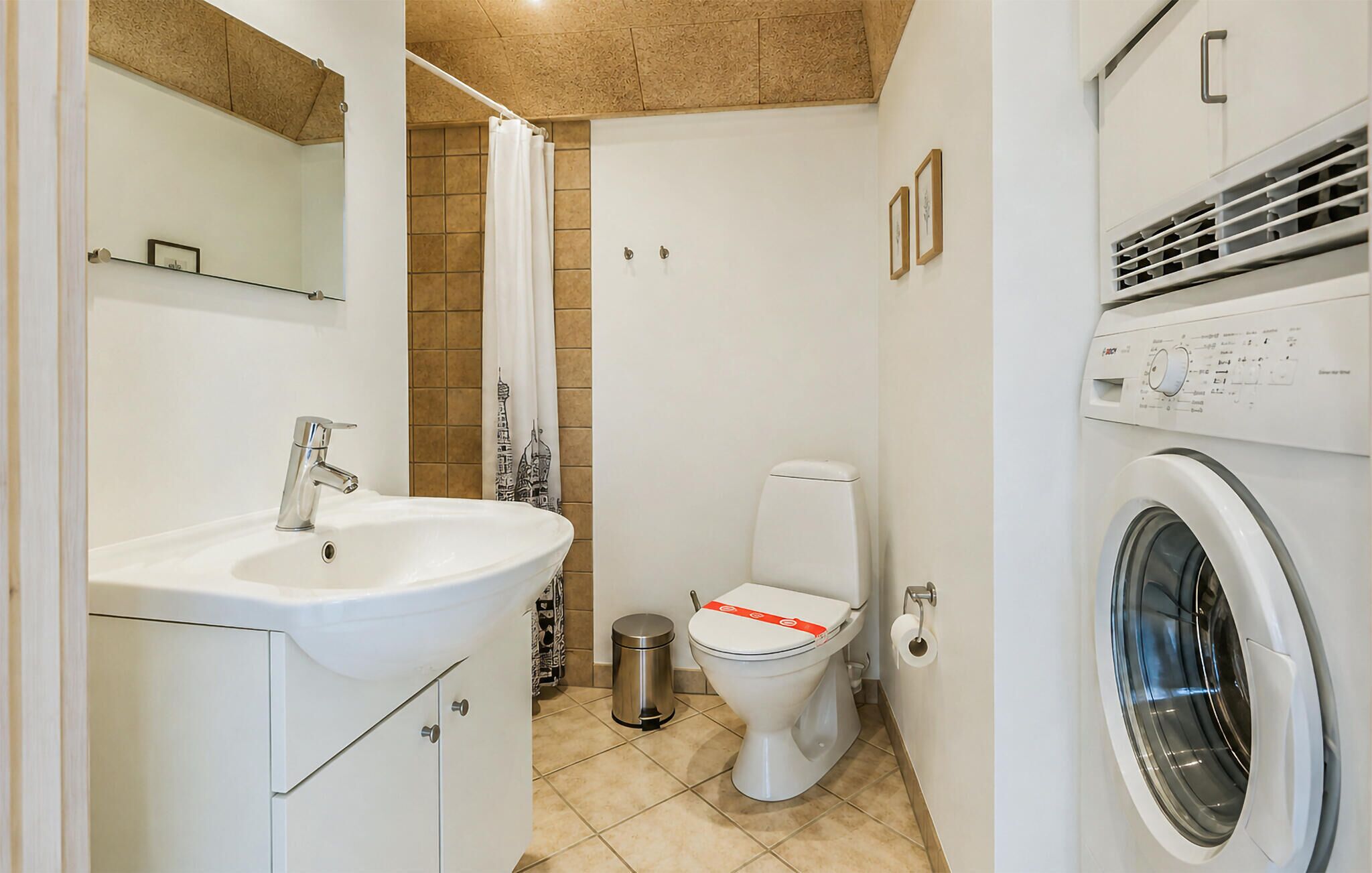 Un baño con lavamanos, inodoro y lavadora.