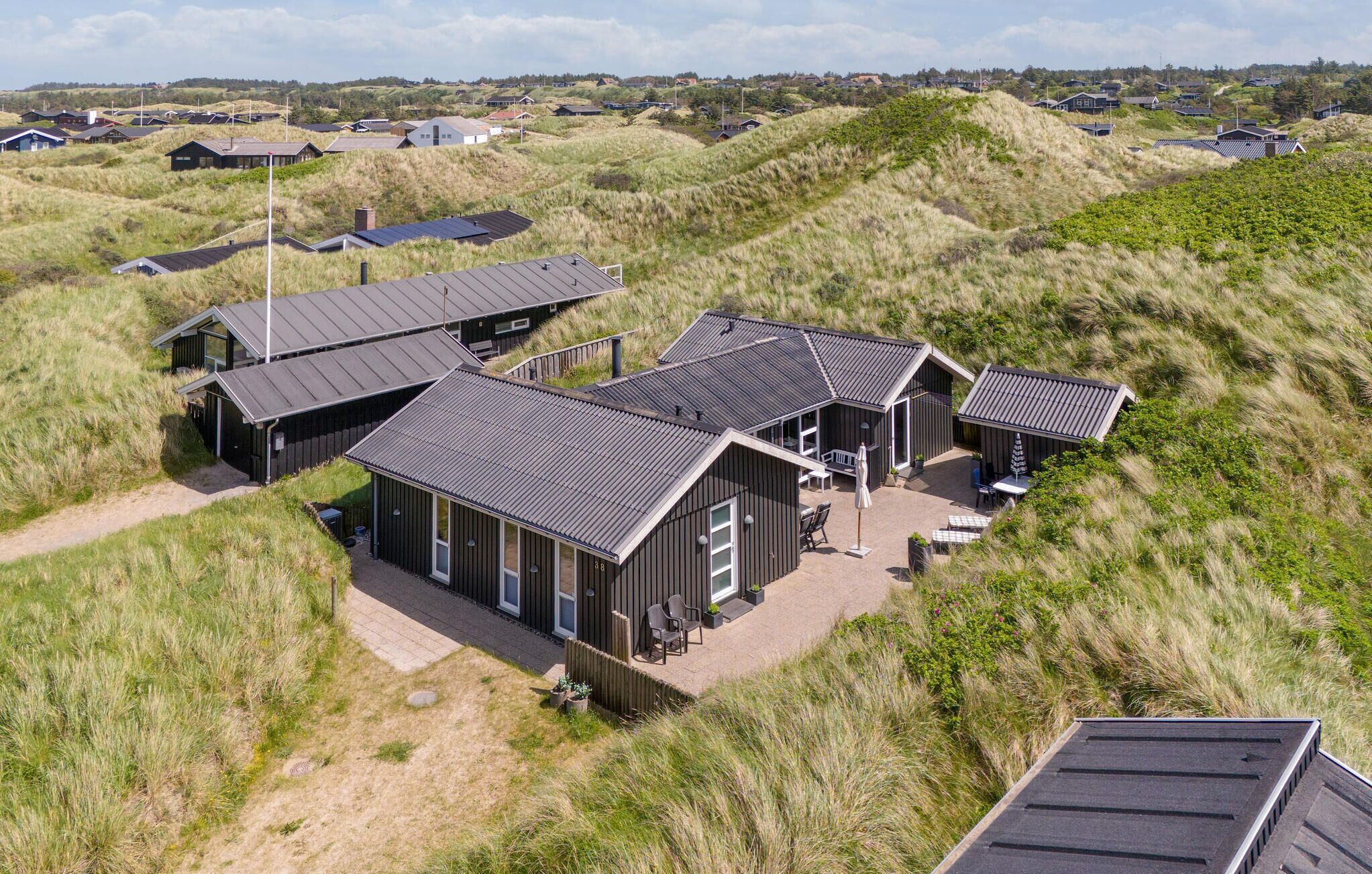 A modern, multi-story building with a flat roof, surrounded by grassy dunes.