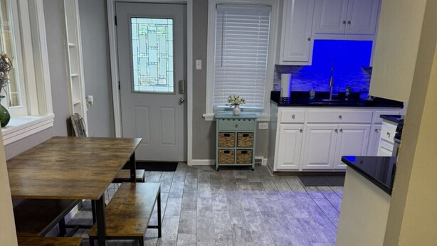 A kitchen with white cabinets, a wooden dining table, and a herringbone-patterned floor. - Perfect for Families, newly remodeled (Glendale)