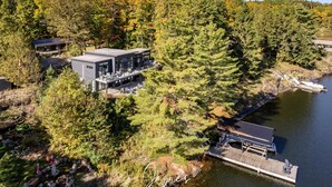 Una casa moderna con una terrazza che si affaccia su un lago, immersa in una fitta foresta.