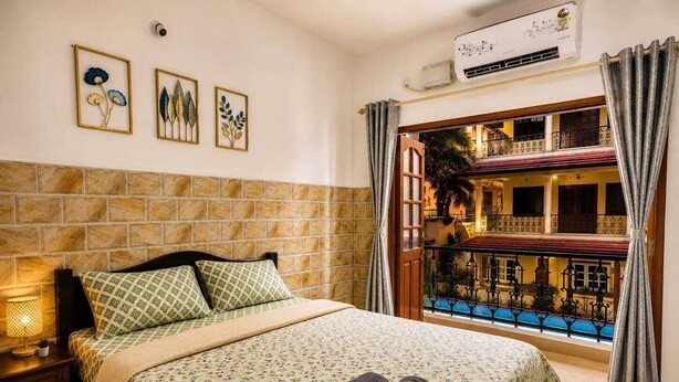 Habitación de hotel con cama, mesita de noche, aire acondicionado de pared y balcón con piscina.