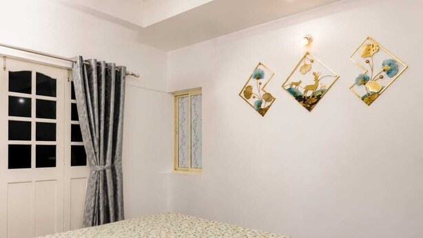 Une chambre à coucher avec un lit, un ventilateur de plafond, une fenêtre avec des rideaux et des œuvres d’art murales.