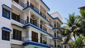 Un hôtel doté d’une piscine, de plusieurs balcons et de palmiers.