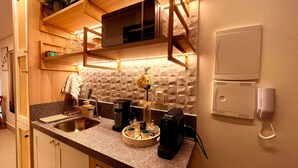 A kitchen with a granite countertop, a coffee maker, a vase with flowers, and a phone on the wall. - Aquamaris Vista Mar Lateral - by Almare (João Pessoa)