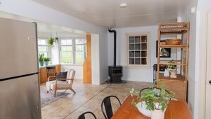 Een ruime keuken met een ingebouwde kookplaat, een houten eettafel en stoelen.