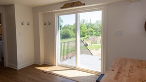 A room with a wooden floor, a sliding glass door leading to an outdoor deck, and a small wooden table. - Amish Cottage, Hot Tub, on Mill Creek (Lancaster)