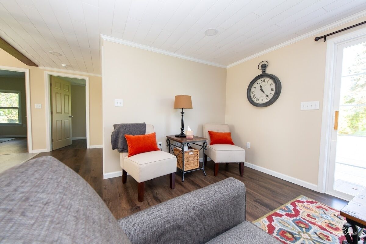 A living room with a sofa, two armchairs, a lamp, a clock, and a patterned rug.
