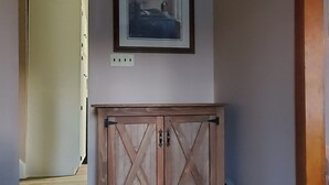 A hallway with a wooden cabinet and a framed picture on the wall.
