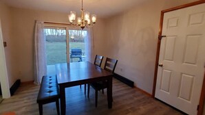 A dining area with a table and chairs, a chandelier, and a door.