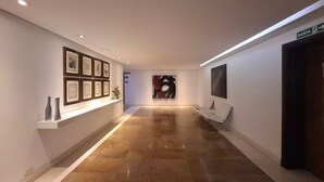A hallway with framed artwork on the walls, a reception desk, and a seating area. - Fully Furnished Apartments in a Building With a Pool Just a few Meters From Av. Paulista Tnps (São Paulo)